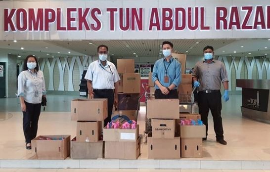 Gor (far left) and Rajendran (second from left) handover the hand sanitizer to the Penang Island City Council