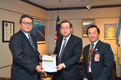 Kawamura (left) and Hun (right) present a donation to Mr. Lim