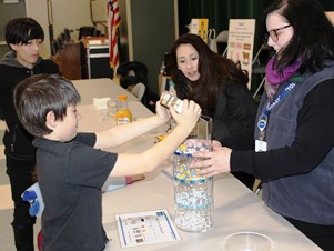 A second grader is excited to pour the capful of particles into the filtration model