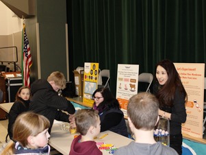 A fifth grader is working hard to draw sugar water from orange juice using a large syringe