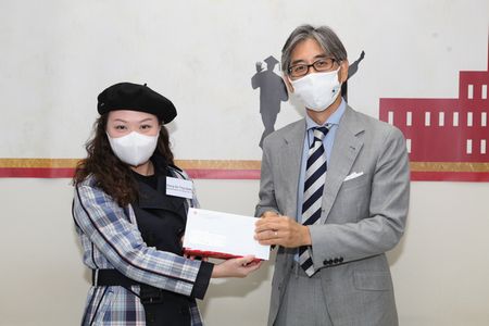 Funahashi (right) presenting the scholarship to a student