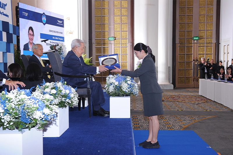 Recipient accepting her award from Privy Council President General Surayud